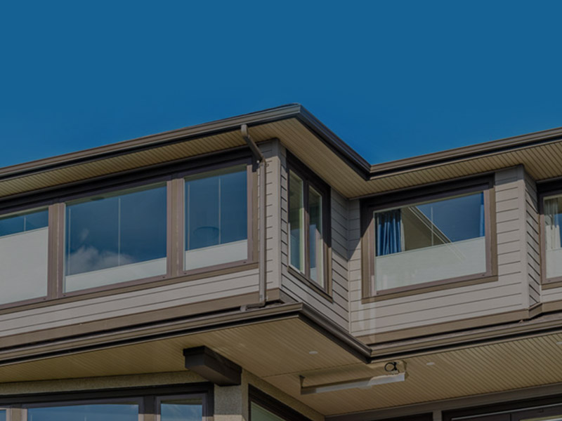 Modern home with metal gutters along the roofline against a blue sky.